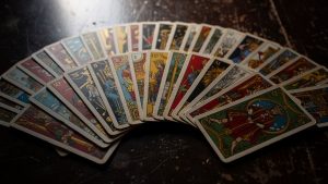 Jeu de 32 cartes étalé sur une table sombre, mettant en valeur les quatre couleurs de cartomancie avec un éclairage cinématographique et un rendu très détaillé.