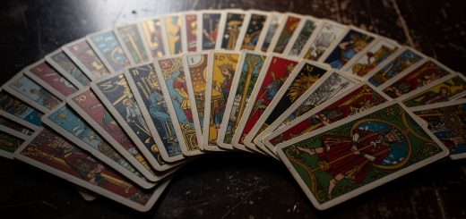 Jeu de 32 cartes étalé sur une table sombre, mettant en valeur les quatre couleurs de cartomancie avec un éclairage cinématographique et un rendu très détaillé.